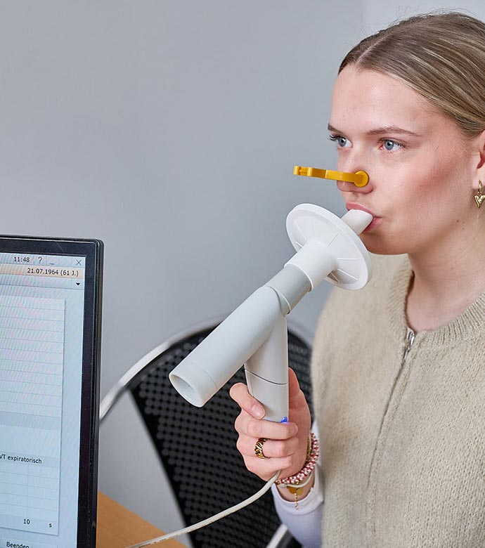 Patientin führt einen Lungenfunktionstest mit Messgerät durch